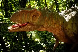 Ilustrasi: Model replika dinosaurus karnivora berukuran besar di antara pepohonan rindang.