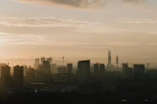 Ilustrasi: Pemandangan siluet deretan gedung pencakar langit berselimut kabut saat fajar.