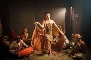 Ilustrasi: Seorang penari perempuan berkemben batik menari diiringi musisi pengrawit tradisional.