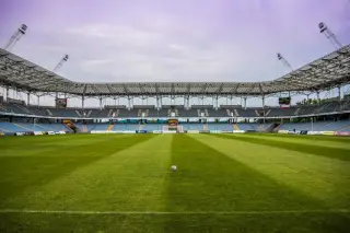 Ilustrasi: Bola tergeletak di tengah lapangan rumput stadion sepak bola yang kosong.