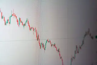 Ilustrasi: Tampilan grafik candlestick pergerakan harga saham berwarna merah dan hijau pada layar monitor.