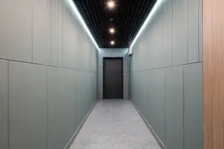 Ilustrasi: Lorong bangunan yang sepi dan bersih dengan dinding polos dan sebuah pintu di ujungnya.