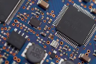 Ilustrasi: Foto makro komponen elektronik dan cip mikroprosesor pada papan sirkuit biru.