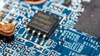Ilustrasi: Foto makro sebuah mikrochip terpasang pada papan sirkuit elektronik berwarna biru.