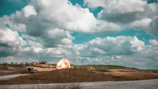 Ilustrasi: Sebuah tank militer menembakkan amunisi di area terbuka di bawah langit berawan.