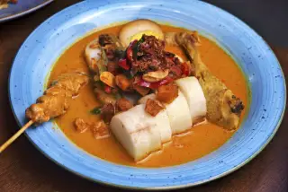 Ilustrasi: Sepiring lontong sayur berkuah kuning dengan ayam, telur, dan sate.