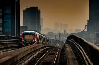 Ilustrasi: Kereta LRT melintas di jalur layang dengan latar belakang gedung-gedung perkotaan Jakarta.