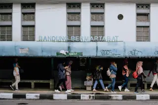 Ilustrasi: Pejalan kaki melintas di depan halte bus bertuliskan Bandung Bermartabat.