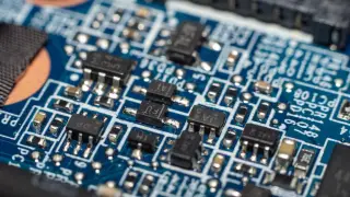 Ilustrasi: Foto makro komponen elektronik dan chip pada papan sirkuit biru.
