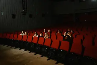 Ilustrasi: Sejumlah penonton berkacamata 3D duduk di antara deretan kursi merah di dalam bioskop yang gelap.