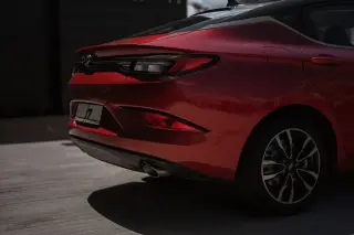 Ilustrasi: Bagian belakang mobil sedan berwarna merah yang terparkir di area terbuka.