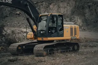 Ilustrasi: Sebuah ekskavator kuning terparkir di area galian berbatu.