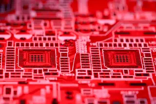 Ilustrasi: Foto jarak dekat papan sirkuit elektronik bernuansa warna merah.