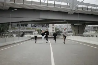 Ilustrasi: Sekelompok pelari berlari bersama di jalan raya perkotaan di bawah jembatan layang.