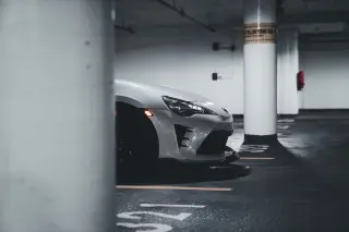 Ilustrasi: Bagian depan mobil sport putih terparkir di dalam gedung parkir bawah tanah.