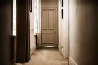 Ilustrasi: Lorong bangunan yang sepi dan kosong dengan pintu tertutup di ujungnya.