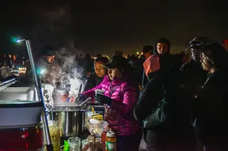 Ilustrasi: Sejumlah orang mengantre di depan pedagang makanan hangat pada malam hari.