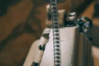 Ilustrasi: Pita seluloid film vintage terpasang pada proyektor dari jarak dekat.