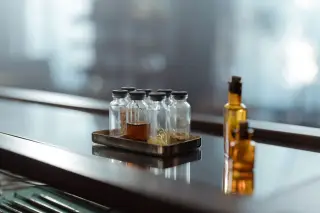 Ilustrasi: Deretan botol kaca kecil dan peralatan medis di atas permukaan meja mengilap.