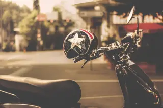 Ilustrasi: Helm bermotif bintang tergantung pada setang skuter di pinggir jalan perkotaan.