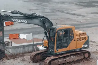 Ilustrasi: Sebuah ekskavator kuning terparkir di area proyek pengerjaan tanah.