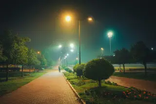 Ilustrasi: Jalan setapak di taman kota pada malam hari yang diterangi deretan lampu taman.