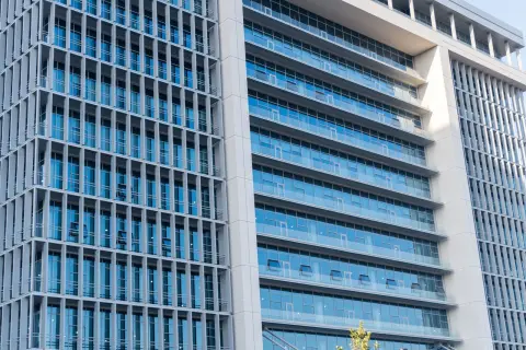 Ilustrasi: Fasad gedung perkantoran modern bertingkat dengan jendela kaca besar.