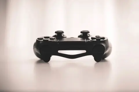 Ilustrasi: Sebuah pengontrol konsol permainan video hitam diletakkan di atas permukaan putih.