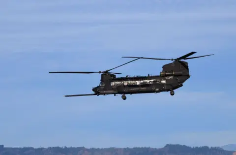 Ilustrasi: Sebuah helikopter militer Chinook terbang di langit berlatar perbukitan.