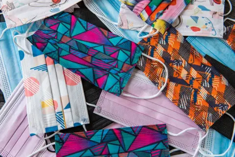 Ilustrasi: Tumpukan masker medis dan masker kain dengan beragam motif warna-warni.