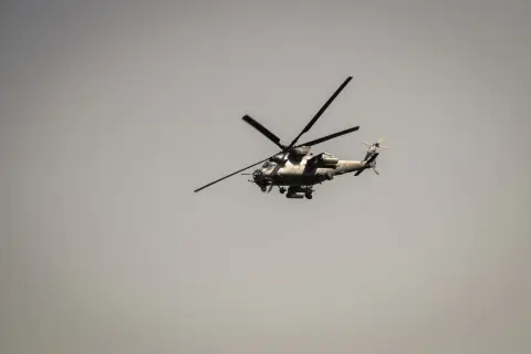 Ilustrasi: Sebuah helikopter militer sedang terbang di langit berawan abu-abu.